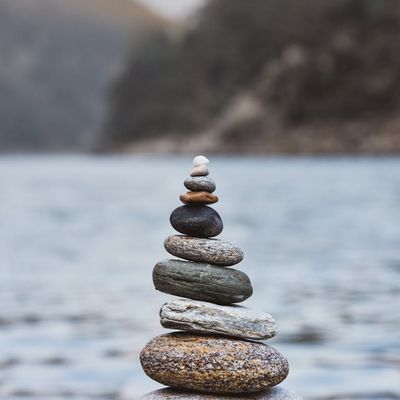 Smooth, dark stones stacked peacefully near calm water.
